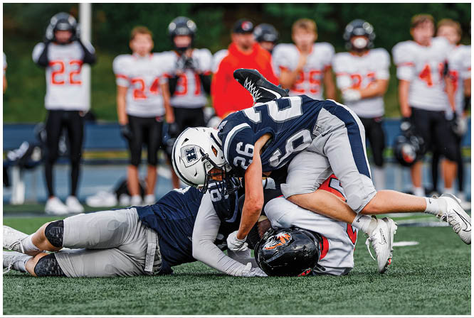 Three football players in blue and white uniforms running on a field. Description generated by AI