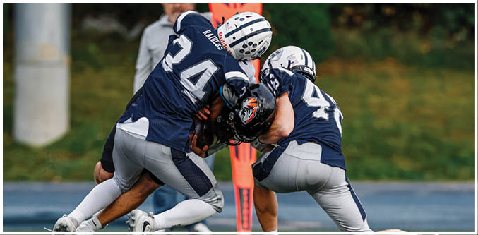 Three football players in blue and white uniforms running on a field. Description generated by AI