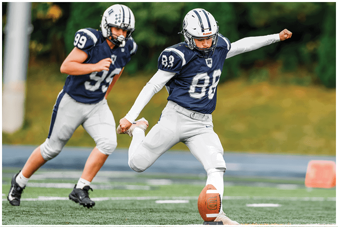 Three football players in blue and white uniforms running on a field. Description generated by AI
