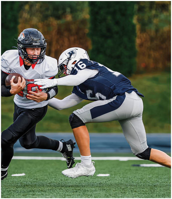 Three football players in blue and white uniforms running on a field. Description generated by AI