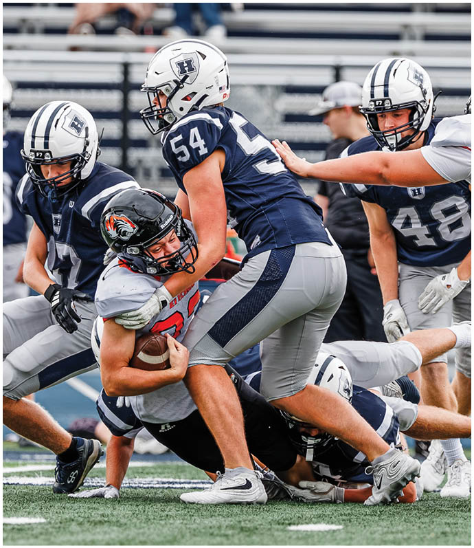 Three football players in blue and white uniforms running on a field. Description generated by AI