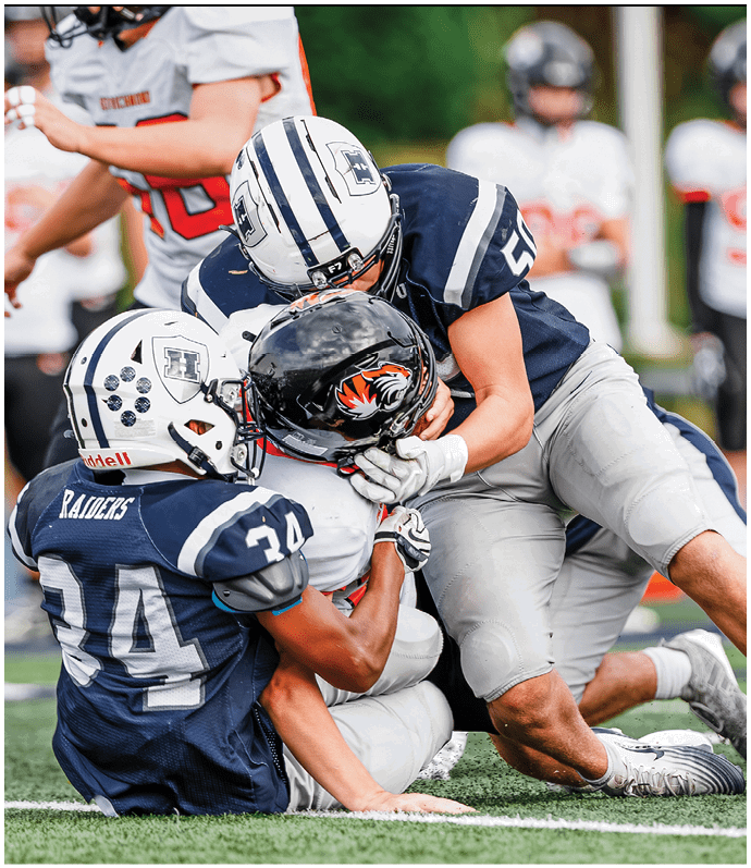 Three football players in blue and white uniforms running on a field. Description generated by AI