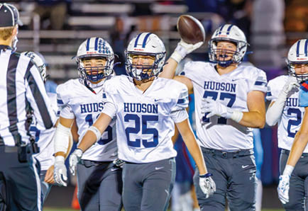 Two adults in football uniforms are actively engaged in a play on a field, with one holding the ball and the other preparing to tackle. Description generated by AI