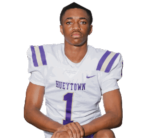 A person wearing a white and purple football uniform with the word “Hueytown" and the number one kneels with hands clasped against a white background. Description generated by AI