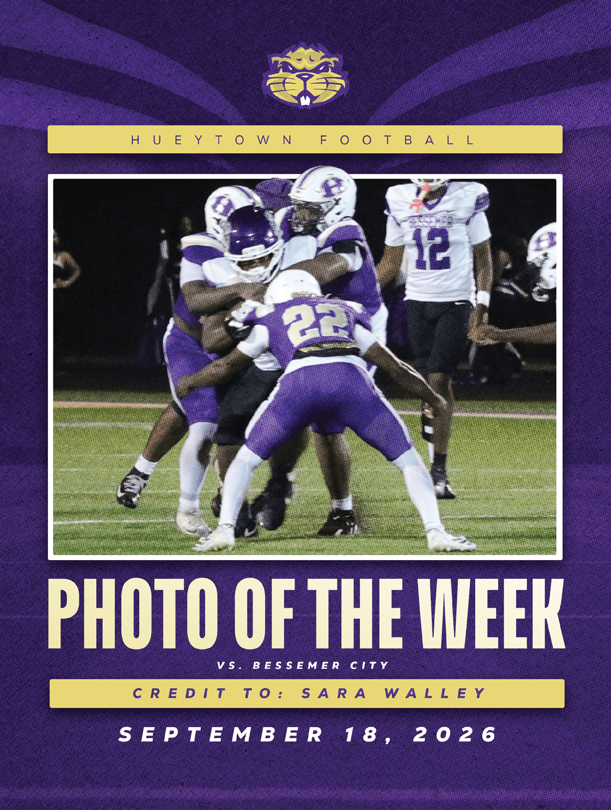 A group of football players in purple and white uniforms are engaged in a tackle during a nighttime game on a grassy field. Description generated by AI