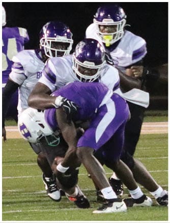 A person wearing a Wildcats football uniform is running on a field while holding a football. Description generated by AI