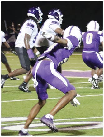 A person wearing a Wildcats football uniform is running on a field while holding a football. Description generated by AI