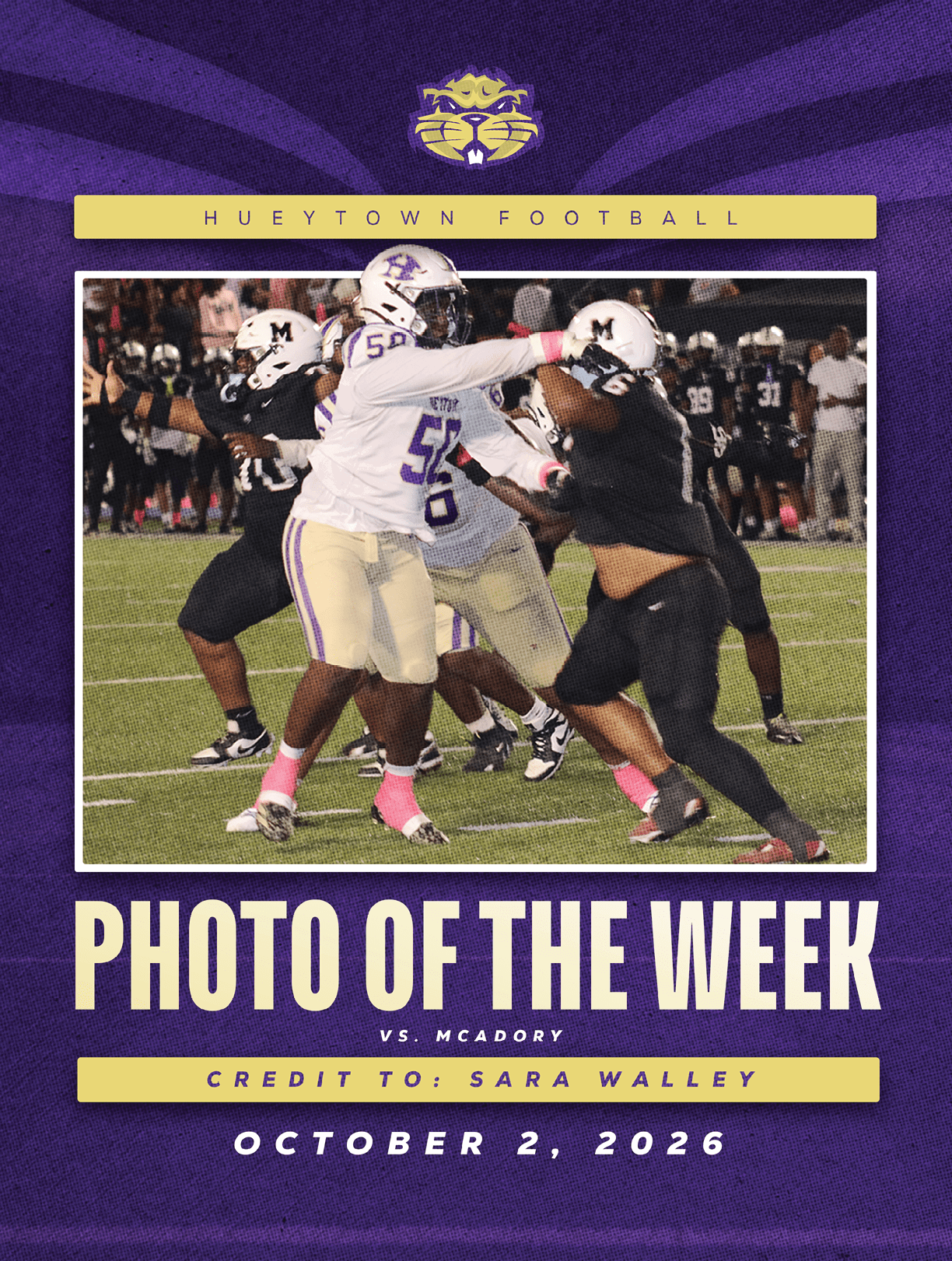 Several football players in purple and white uniforms are engaged in a tackle on a grassy field during a nighttime game. Description generated by AI