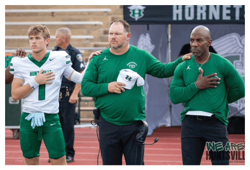 Two football players wearing black jerseys and holding hands. Description generated by AI