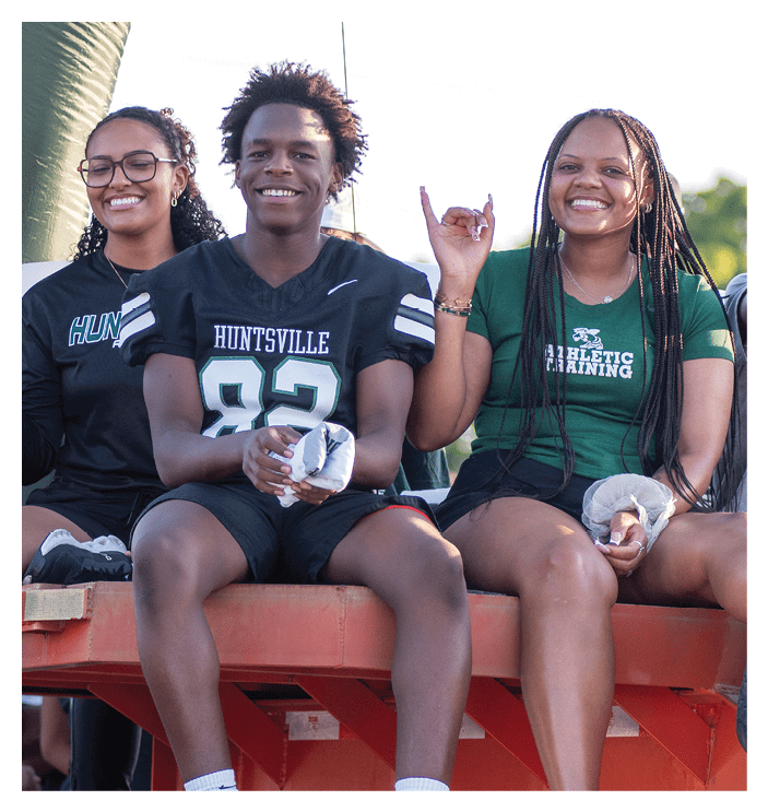 A football game is in progress with players on the field. One player is throwing a football while another player is trying to catch it. The players are wearing uniforms and are actively engaged in the game. AI generated content