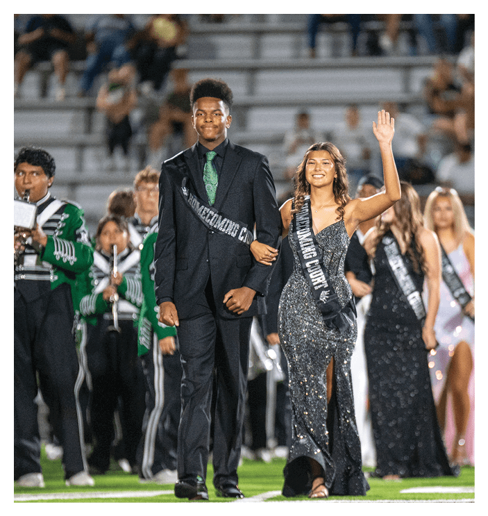 A football game is in progress with players on the field. One player is throwing a football while another player is trying to catch it. The players are wearing uniforms and are actively engaged in the game. AI generated content