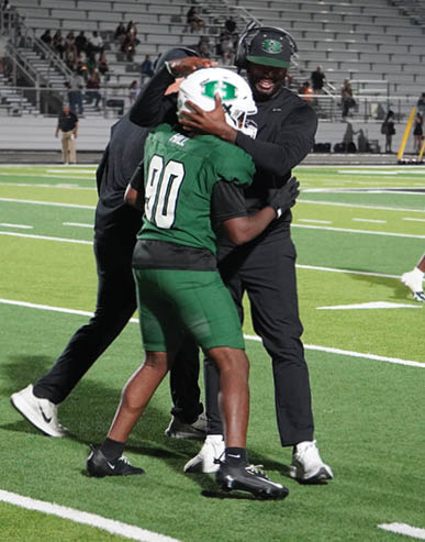 Two men embrace on a field, one wearing a black shirt and the other wearing a black and white shirt. AI generated content