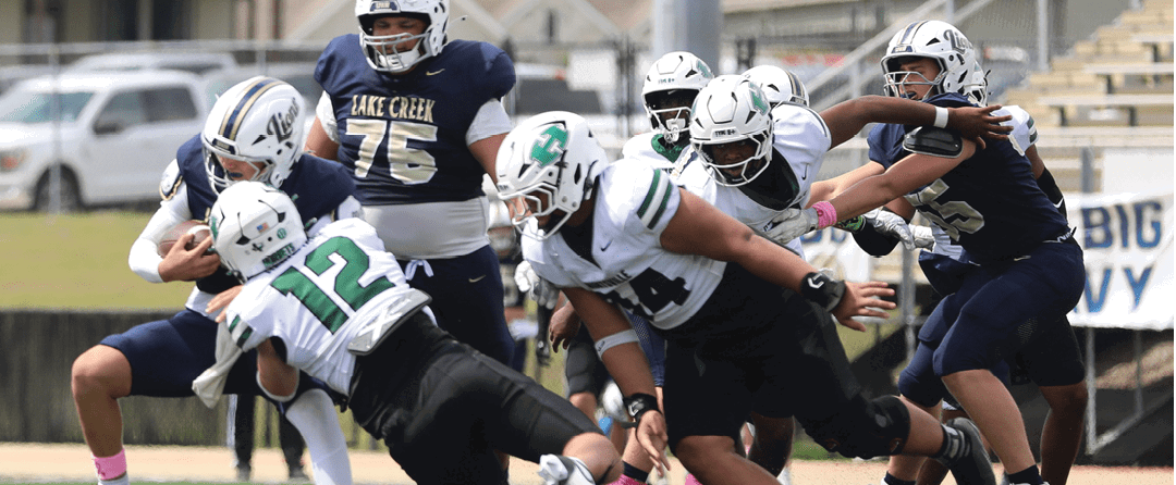Four people wearing black sports jerseys with “VISTA" on them stand closely together in front of a large crowd, with one person raising an arm in celebration. Description generated by AI