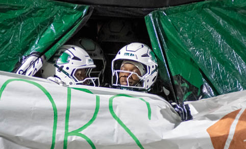 Two men wearing football uniforms are hugging each other on a field. AI generated content