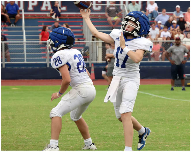 Three football players in blue and white uniforms running on a field. Description generated by AI