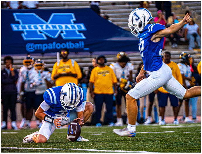 Three football players in blue and white uniforms running on a field. Description generated by AI