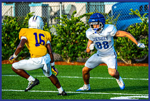 Three football players in blue and white uniforms running on a field. Description generated by AI