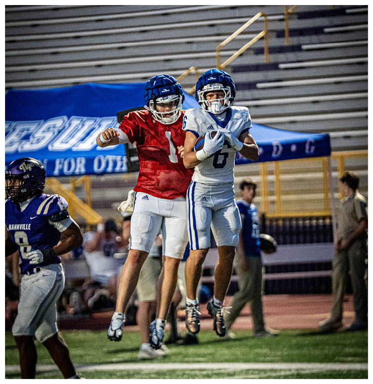 Two football players wearing black jerseys and holding hands. Description generated by AI