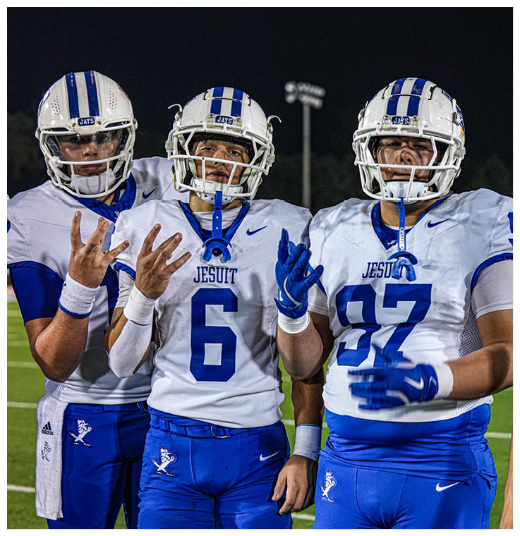 Two football players wearing black jerseys and holding hands. Description generated by AI