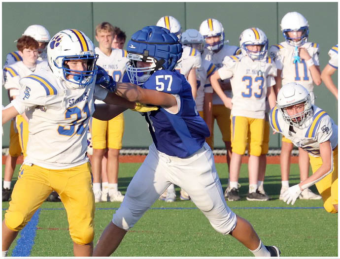 Three football players in blue and white uniforms running on a field. Description generated by AI