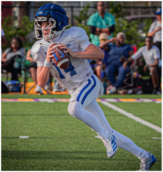 Three football players in blue and white uniforms running on a field. Description generated by AI
