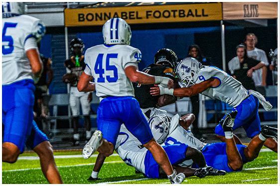 Three football players in blue and white uniforms running on a field. Description generated by AI