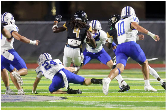 Three football players in blue and white uniforms running on a field. Description generated by AI