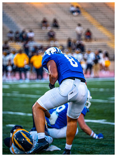 Two football players wearing black jerseys and holding hands. Description generated by AI