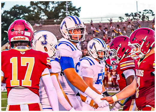 Three football players in blue and white uniforms running on a field. Description generated by AI