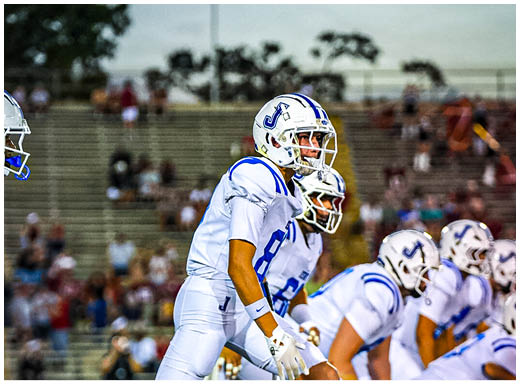 A football player wearing a blue and white uniform. Description generated by AI