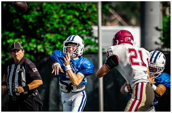 Three football players in blue and white uniforms running on a field. Description generated by AI