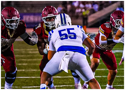 Three football players in blue and white uniforms running on a field. Description generated by AI