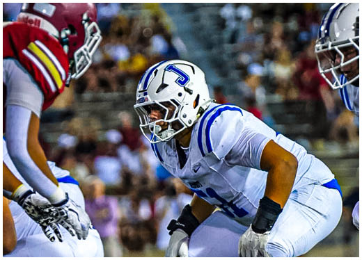 Three football players in blue and white uniforms running on a field. Description generated by AI