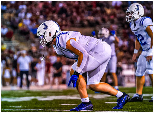 A football player wearing a blue and white uniform. Description generated by AI