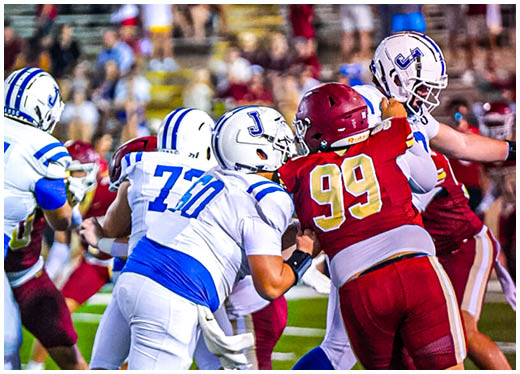 Three football players in blue and white uniforms running on a field. Description generated by AI