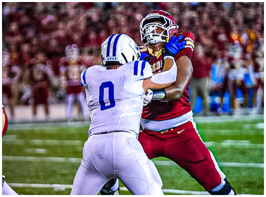 A football player wearing a blue and white uniform. Description generated by AI