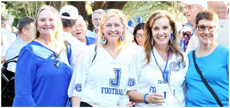 Three football players in blue and white uniforms running on a field. Description generated by AI