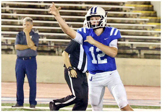 Three football players in blue and white uniforms running on a field. Description generated by AI