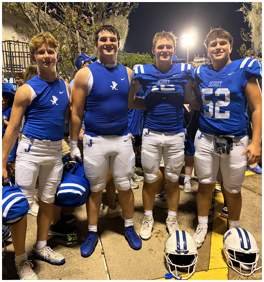 Three football players in blue and white uniforms running on a field. Description generated by AI