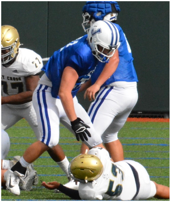 Three football players in blue and white uniforms running on a field. Description generated by AI