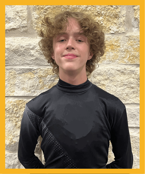 A person with curly hair wearing a black football uniform with “VISTA" on the jersey is sitting on a grassy field with one leg bent and the other extended. Description generated by AI