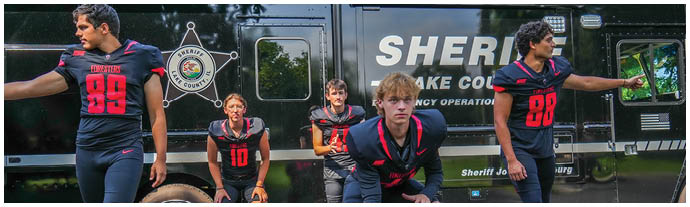 A group of men standing in front of a black truck. Description generated by AI