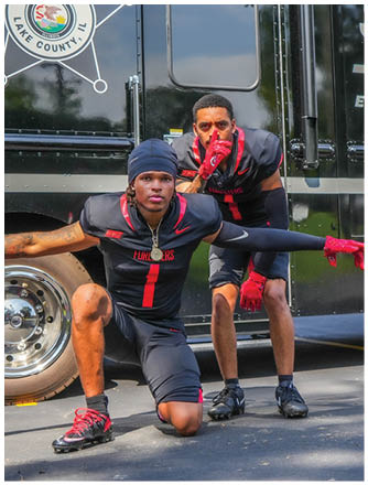 Two men posing in front of a police truck. Description generated by AI