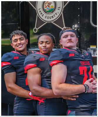 Three men wearing football uniforms pose for a picture. Description generated by AI