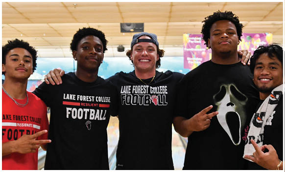 A group of men wearing black shirts and posing for a picture. Description generated by AI