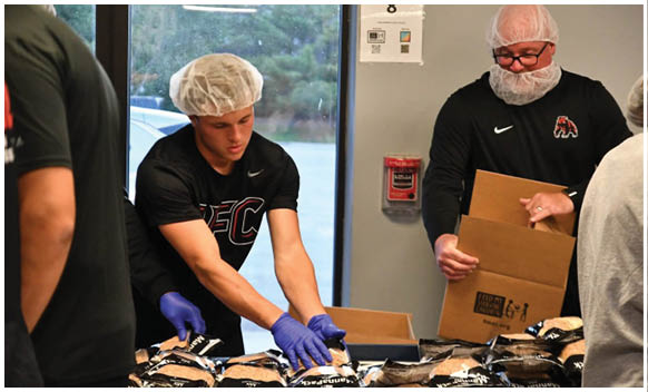 A man wearing a Nike shirt is reaching for a box. Description generated by AI