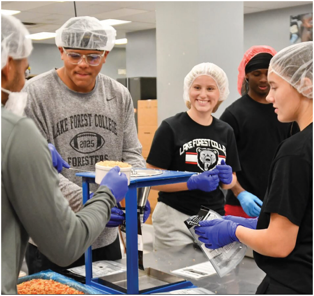 A group of people wearing hairnets and gloves are working together to prepare food. Description generated by AI