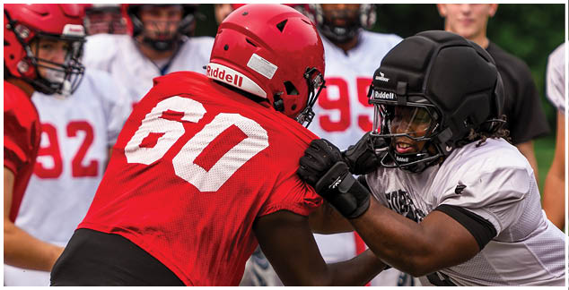 A football player wearing a red jersey with the number 60 on it. Description generated by AI