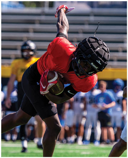 A football player in a red jersey catching a ball. Description generated by AI