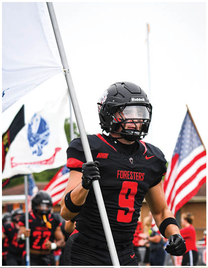 A football player wearing a black jersey with the number 9 on it. Description generated by AI